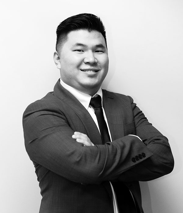 A black and white photo of an asian man in a suit.